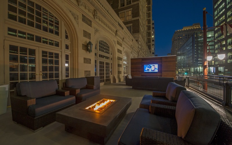 an outdoor lounge with a tv, chairs and a firepit